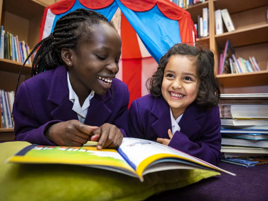 Smiling children reading together in the library