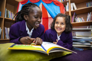 Smiling children reading together in the library