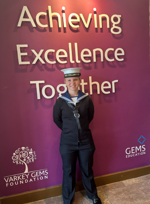 Webber student in Navy uniform under the excellence wall