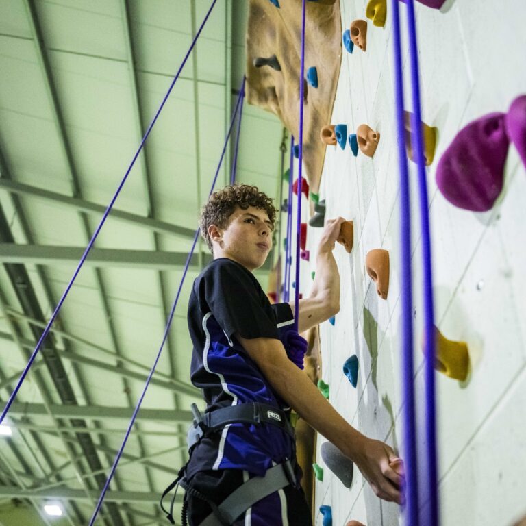 senior student climbing rock wall