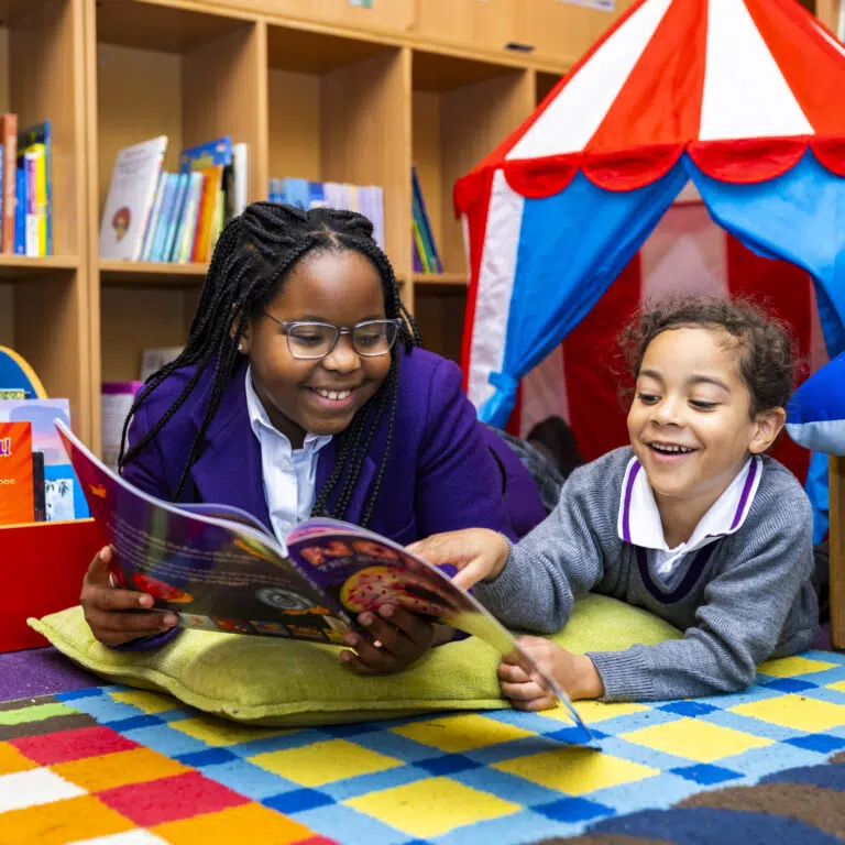 Two reception children enjoying a book in the library