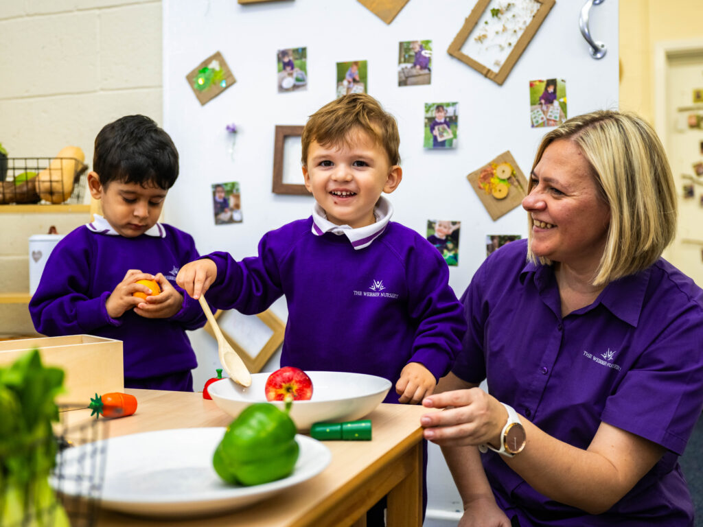 Nursery children role play with food and nursery worker