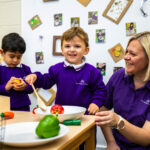 Nursery children role play with food and nursery worker