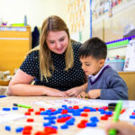 reception child working with teaching, laughing